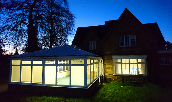 Building with conservatory lit up, pictured at dusk
