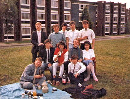 11 smartly dressed students outside halls, including drinks and a picnic rug,