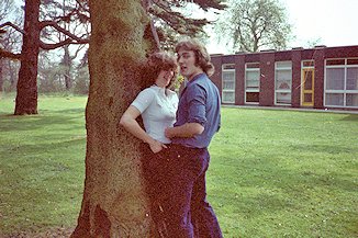 Male and female student close together by a tree