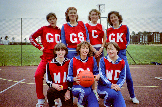 Seven female basketball players pose on the court